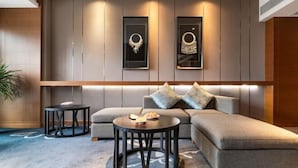 A modern living room with a sectional sofa, two round tables, and framed wall art. - Kai Li Heaven-sent Resort Hotel (Kaili)