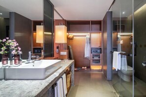 A modern bathroom with a large mirror, a marble sink, and a glass shower enclosure.