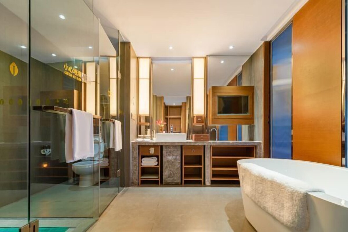A modern bathroom with a glass shower enclosure, a bathtub, a vanity with a sink, and a large mirror.