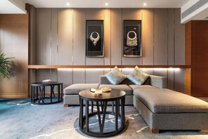A modern living room with a sectional sofa, two round black tables, and framed wall art.
