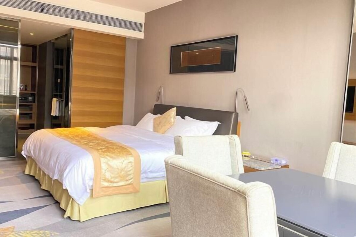 A hotel room with a bed, a desk, a chair, and a wardrobe.