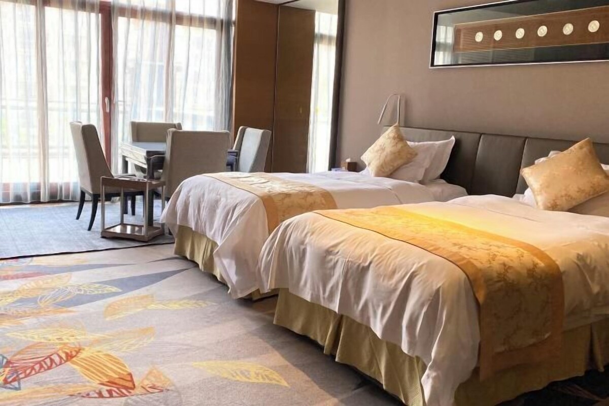 A hotel room with two beds, a desk, and a chair.