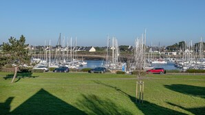 A marina with multiple sailboats docked, a grassy area in the foreground, and a few cars parked along the side. - House for 6 - Cap sur l'Océan - Pool (Arzon)