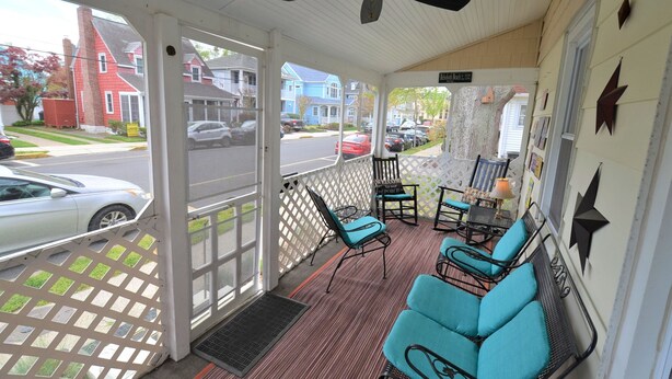 A covered porch with a ceiling fan, outdoor seating with blue cushions, and a view of the street and houses. - Just 1.5 Blocks to the Beach and Boardwalk! (Rehoboth Beach)