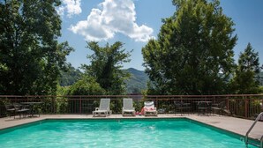 Piscina con sillas de descanso y vistas a una cadena montañosa.