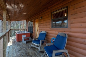 A wooden cabin with a porch, two chairs, a hot tub, and a window. - Gorgeous Mountain Views/Hot Tub (Sevierville)