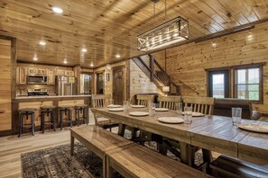 A wooden interior with a dining table set for four, kitchen area, and a staircase.