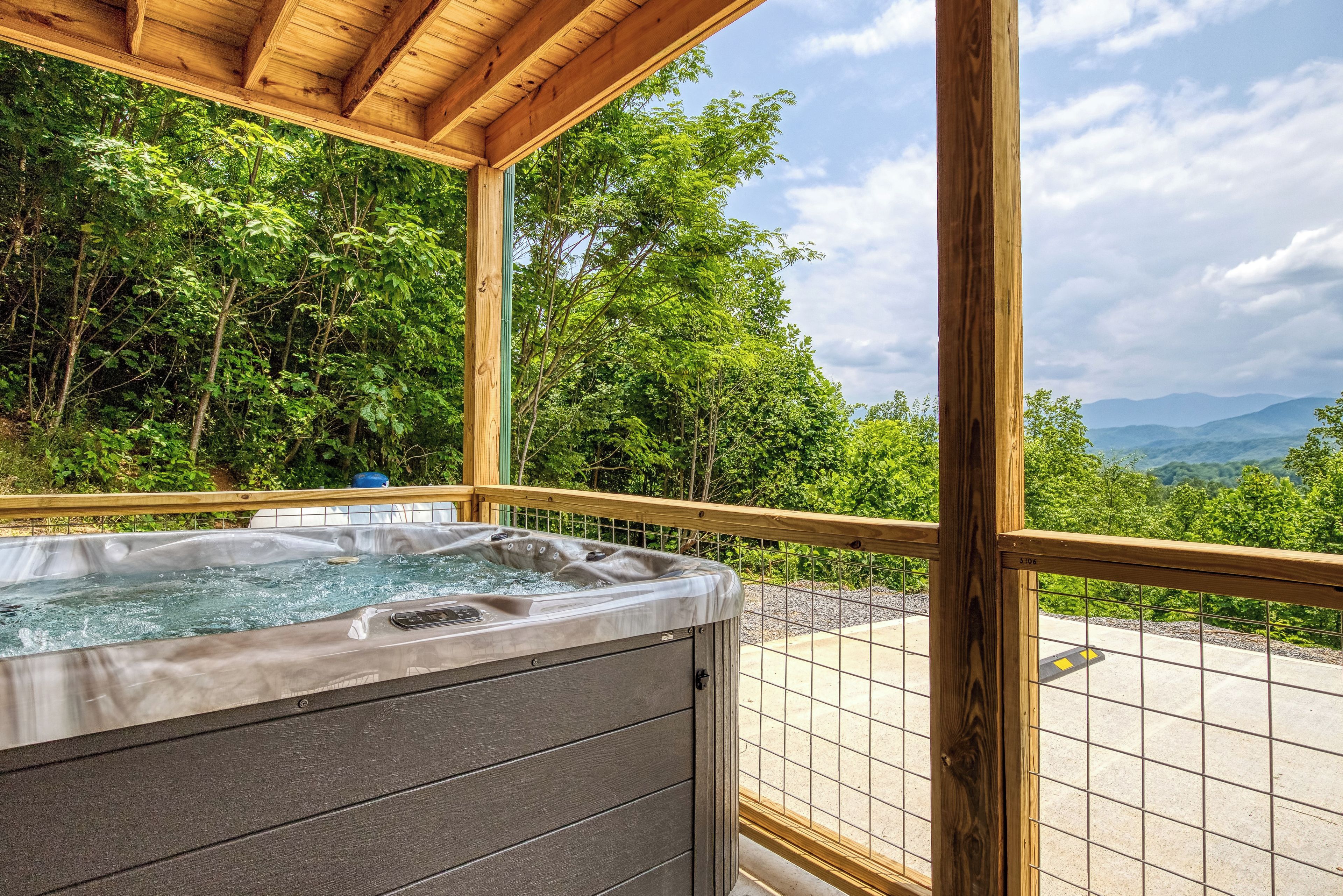 A hot tub with a wooden deck and a view of a mountainous landscape.