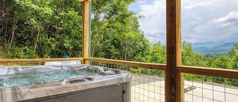 Un jacuzzi con una terraza de madera y vistas a un paisaje montañoso.