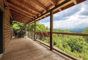 A wooden deck with a view of a forest and mountains.