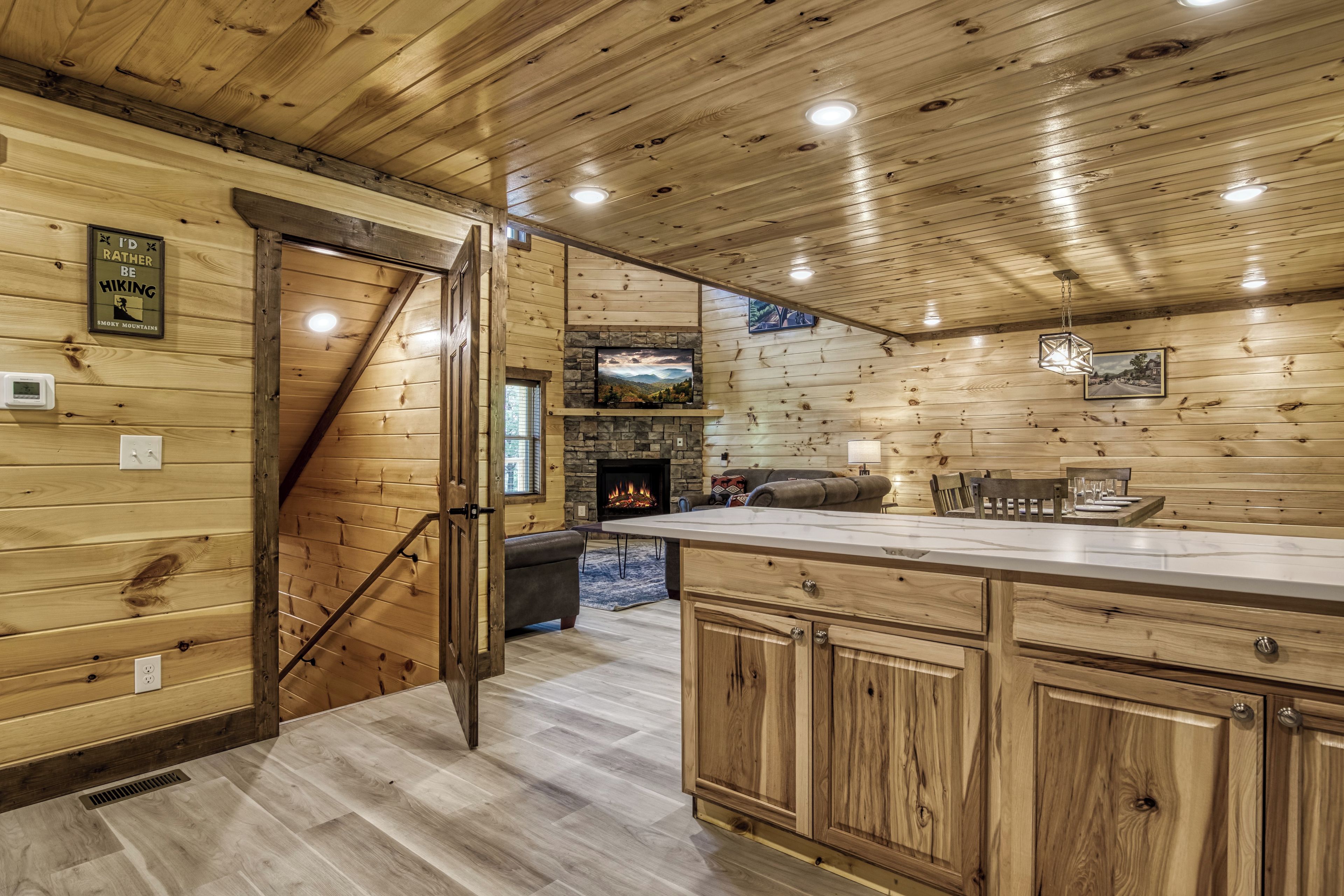A wooden interior with a fireplace, a dining area, and a kitchen with wooden cabinets.