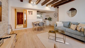 A spacious living area with a wooden floor, a sofa, a coffee table, and a dining table with chairs.
