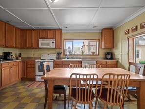 A kitchen with wooden cabinets, a microwave, a stove, and a dining table with chairs.