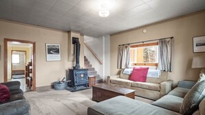 A living room with a sofa, a wooden coffee table, a fireplace, and a staircase leading to another room.