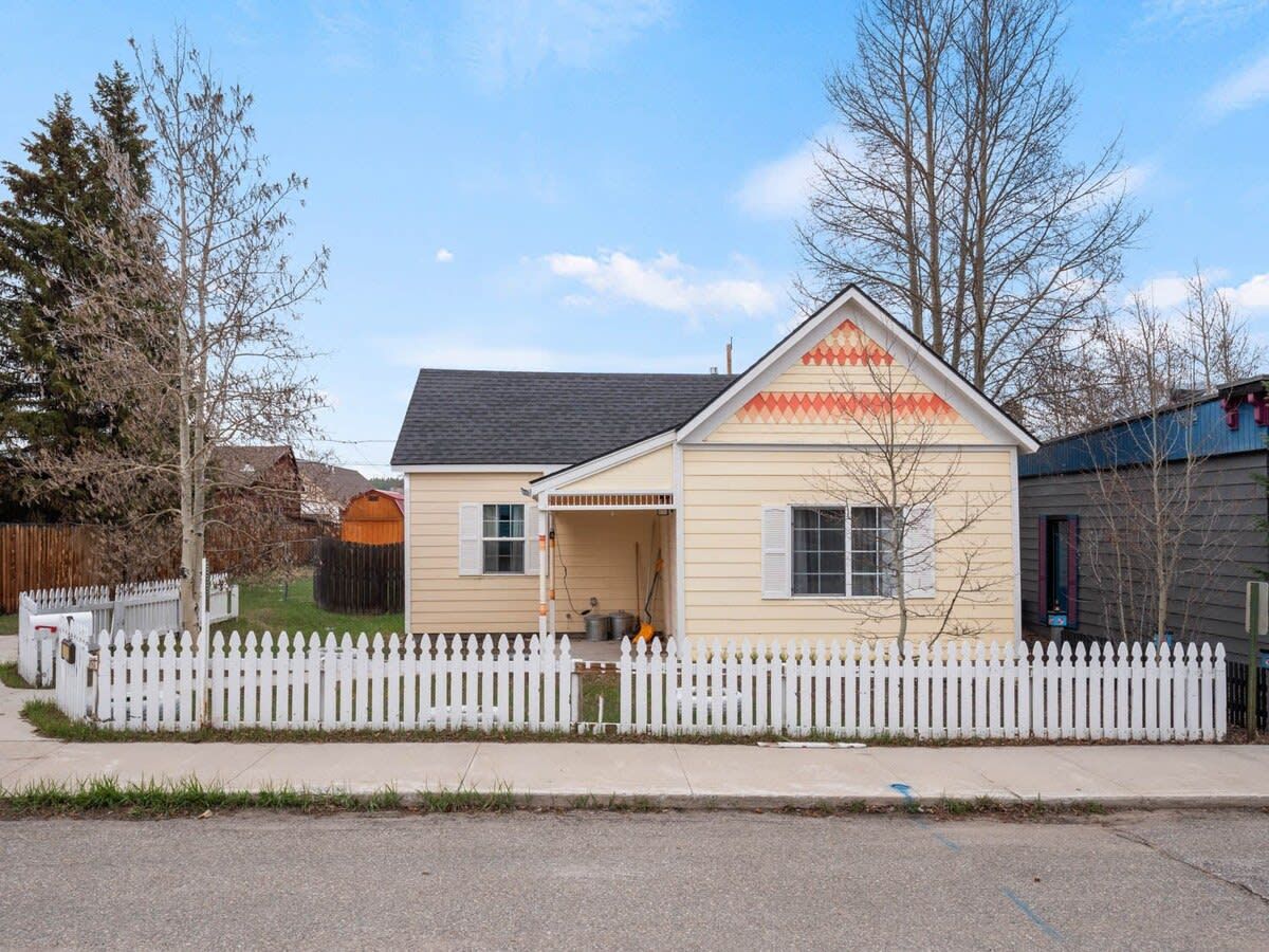 A single-story house with a white picket fence, a front porch, and a garage.