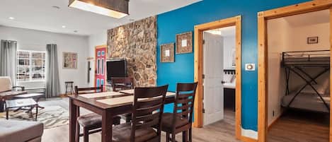 Una sala moderna con comedor, pared de piedra y vistas al exterior.