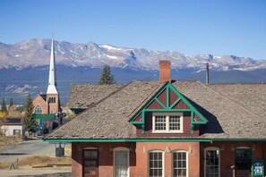 A building with a prominent steeple and a brick facade, set against a mountainous backdrop.