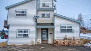 Une maison à deux étages, avec des fondations en pierre, une antenne parabolique et une porte de garage.