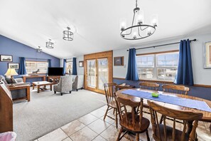 Un salón espacioso con comedor, ventanas amplias y vistas al exterior.