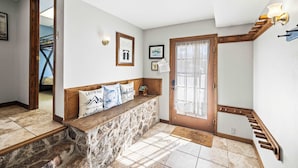 Un banc en pierre avec un dossier en bois, un escalier en bois et une porte dotée d’un panneau de verre.