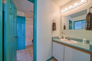 A bathroom with a blue door, a white sink, a mirror with lights, and a towel rack. - The Giddy Betsy — 3BR Cabin + Loft, Sleeps 8 near Twin Lakes & Mt. Elbert (Leadville)