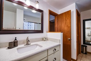 Une salle de bain avec un grand miroir, un lavabo et une porte en bois.
