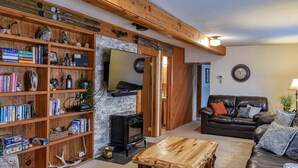 Una sala de estar acogedora con chimenea, un sofá de cuero y una estantería llena de libros y objetos decorativos.