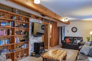 Een gezellige woonkamer met een open haard, een leren bank en een boekenplank vol boeken en decoratieve objecten.