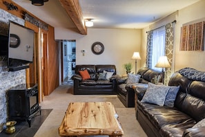 A living room with a fireplace, two leather sofas, a coffee table, and a television.