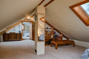 Slaapkamer in een loft met schuine wanden, een houten dressoir, een spiegel, een bed en een boekenkast.