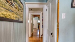 Un pasillo con piso de madera, puertas blancas y un cuadro enmarcado en la pared.