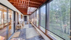 Una habitación amplia con ventanas grandes, techo de madera y vistas al bosque.