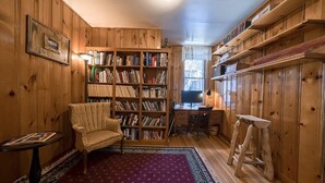 A cozy room with wooden walls, a large bookshelf, a desk, and a chair. - Josephine — Restored 4BR Victorian, Hot Tub, Walk to Main St Leadville, Sleeps 8 (Leadville)