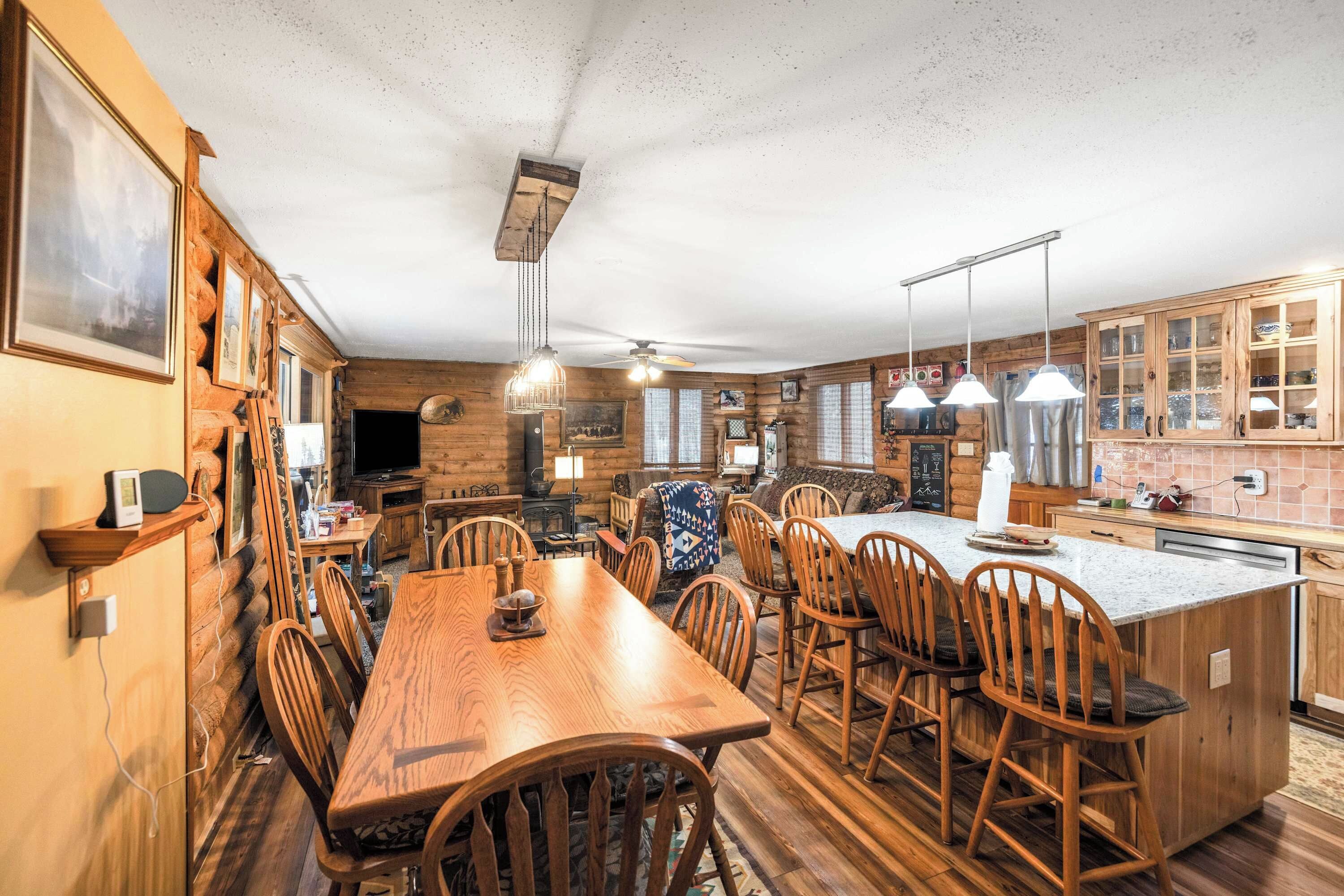 Une cuisine aménagée dans le style d’un chalet en rondins, avec des meubles en bois, une table à manger et un îlot central.