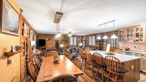 Una cucina in stile baita con arredamento in legno, un tavolo da pranzo e un'isola centrale.