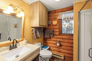 A bathroom with a wooden wall, a sink, a toilet, and a window with a view of trees. - 2BR Cabin–Deck Lake View & Access–BBQ, Pets OK! (Leadville)