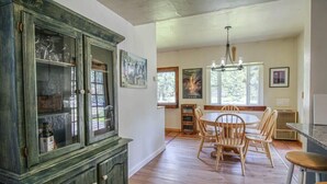 A dining area with a wooden table, chairs, and a chandelier. - 3BR Cozy Cabin - Tranquil Forest - Pet Friendly (Leadville)