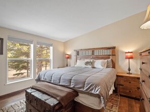 Une chambre à coucher avec un grand lit, deux tables de chevet avec des lampes, un banc en bois et une commode.