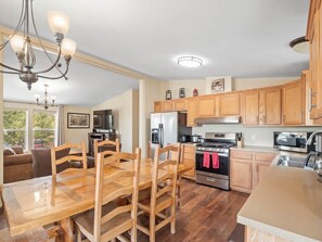 A modern kitchen with wooden cabinets, a dining table with chairs, a refrigerator, stove, and a microwave. - 3BR Mountain View - Covered Patio - Pet Friendly (Leadville)