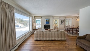 A living room with a sofa, dining table, chairs, and artwork on the walls. - The Shamrock — 5BR Leadville Home, Game Room + 2-Car Garage, Sleeps 10 (Leadville)