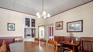 A dining room with a large wooden table, chairs, a bench, and a chandelier. - The Painted Lady — Victorian 4BR Steps to Main St Leadville, Sleeps 10, Dogs OK (Leadville)