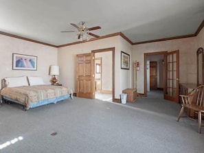 A bedroom with a bed, a ceiling fan, wooden doors, and a chair. - The Painted Lady — Victorian 4BR Steps to Main St Leadville, Sleeps 10, Dogs OK (Leadville)