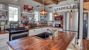 A kitchen with a wooden island, stainless steel appliances, and a 'Leadville' sign on the wall. - Mountain-View Cabin w/ Fireplace & Deck (Twin Lakes)