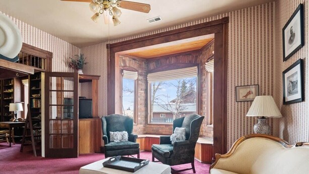 A cozy living room with a fireplace, a sofa, two armchairs, a coffee table, and a bookshelf. - Historic 3BR w/ Loft:Mountain View & Near Town (Leadville)