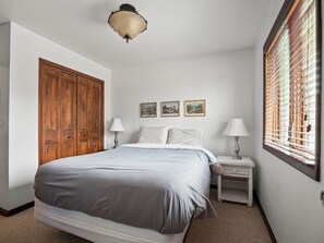 A bedroom with a bed, bedside tables, a wardrobe, and a window with blinds.