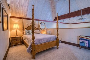 A four-poster bed with a wooden frame, a bedside table with a lamp, a mirror, and a colorful blanket on a carpeted floor. - The Rosemont — Historic 4BR Leadville Victorian, Loft, Fireplace, 2 Blocks Down (Leadville)