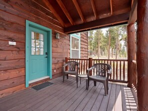 A wooden cabin with a turquoise door, a porch with two chairs, and a view of trees. - NEW LISTING | Mt. Elbert View Cabin | Sleeps 4 | Leadville (Leadville)