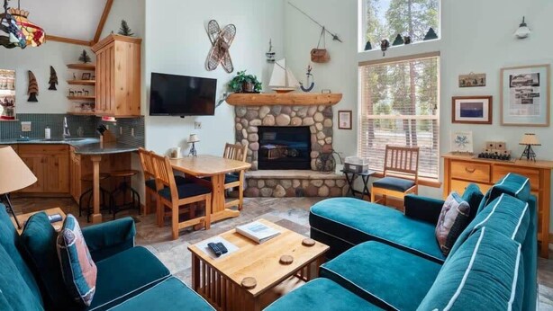 Una sala de estar acogedora con chimenea, televisor y un ventanal grande.