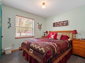 A bedroom with a bed, a window, a nightstand, and wall decorations. - Mt. Elbert View Cabin | Sleeps 4 | Leadville (Leadville)