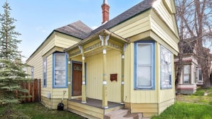 A two-story house with a porch, a chimney, and a small front yard. - Historic 2BR Home, Downtown Leadville, Mountain Vi (Leadville)
